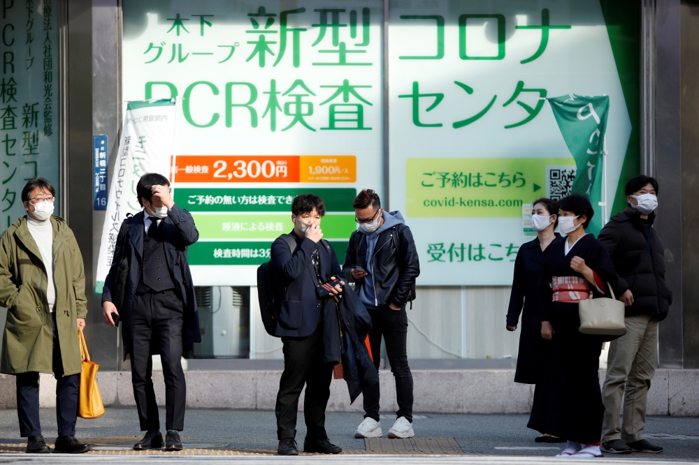 People wait to cross the street in front of a PCR testing centre, on the first day of Japan's closed borders to prevent the spread of the Omicron variant of coronavirus, in Tokyo, Japan November 30, 2021. REUTERS/Androniki Christodoulou