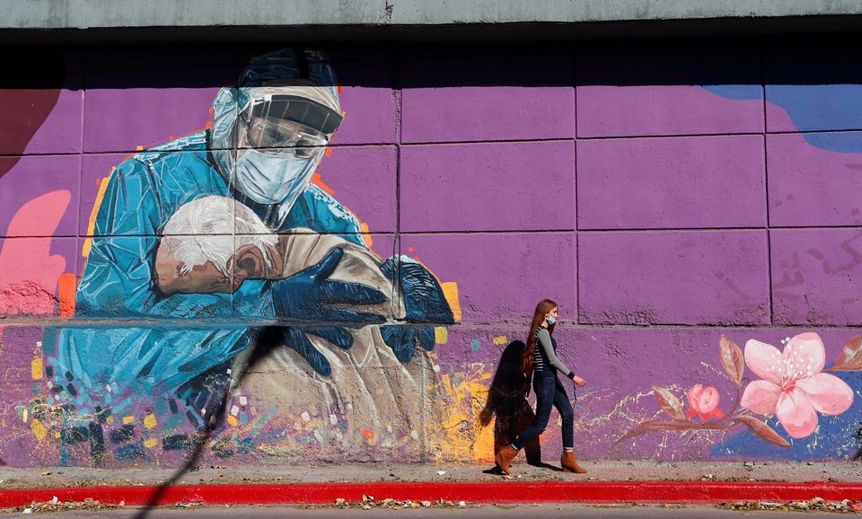 A woman walks past a graffitti depicting a healthcare worker embracing a man, during the coronavirus disease (COVID-19) pandemic, in Cordoba, Argentina, July 10, 2021. REUTERS/Agustin Marcarian/Files

