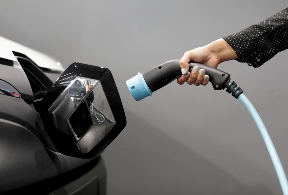 A woman holds a cable to charge a Renault Kangoo ZE electric utility vehicle at a Renault dealership in Cagnes-Sur-Mer, France, October 22, 2020. REUTERS/Eric Gaillard/File Photo/File Photo