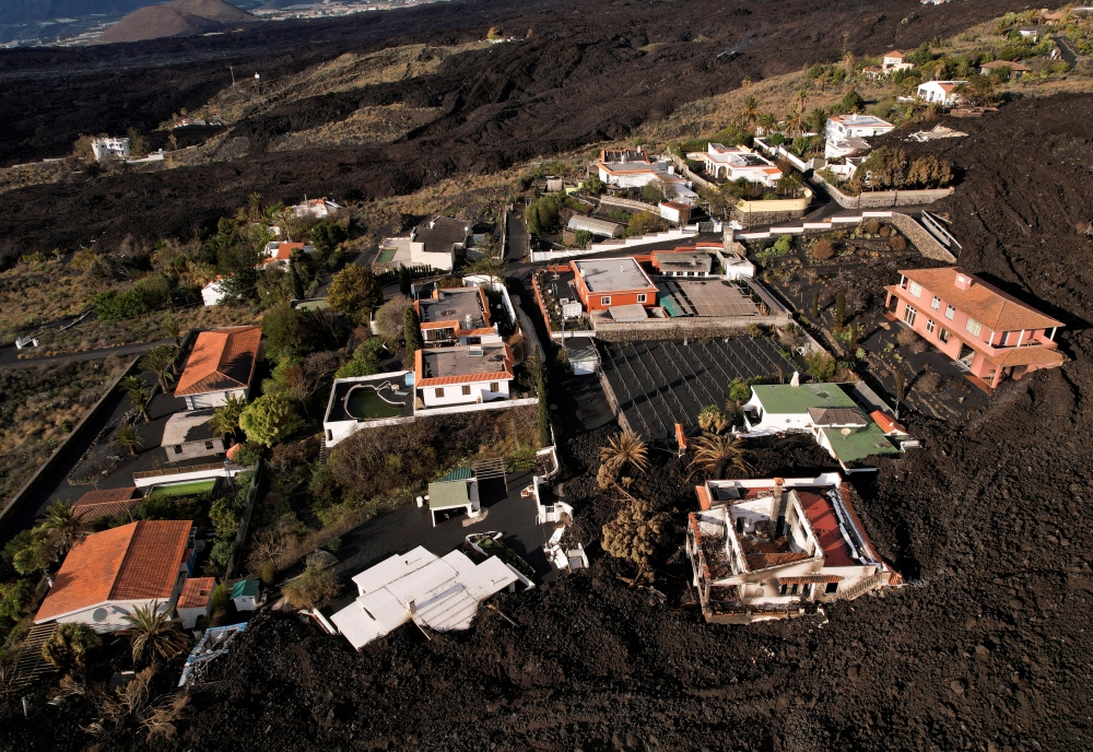 Aerial view of a group of houses surrounded by the lava of the Cumbre Vieja volcano in an exclusion zone in Las Manchas, on the Canary Island of La Palma, Spain, December 17, 2021. Picture taken with a drone. REUTERS/Borja Suarez/File Photo