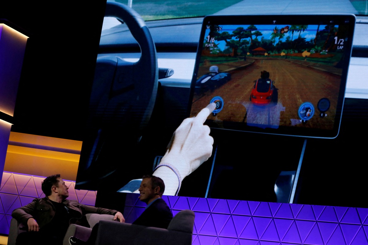FILE PHOTO: Tesla CEO Elon Musk, at the E3 gaming convention in Los Angeles, California,U.S., June 13, 2019, watches a clip of a videogame in a Model 3 vehicle. REUTERS/Mike Blake/File Photo
