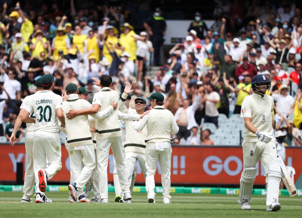 Mitchell Starc of Australia celebrates with teammates after dismissing Joe Root of England in the third Ashes test at Melbourne Cricket Ground in Melbourne, Australia, December 26, 2021. Reuters/Loren Elliott