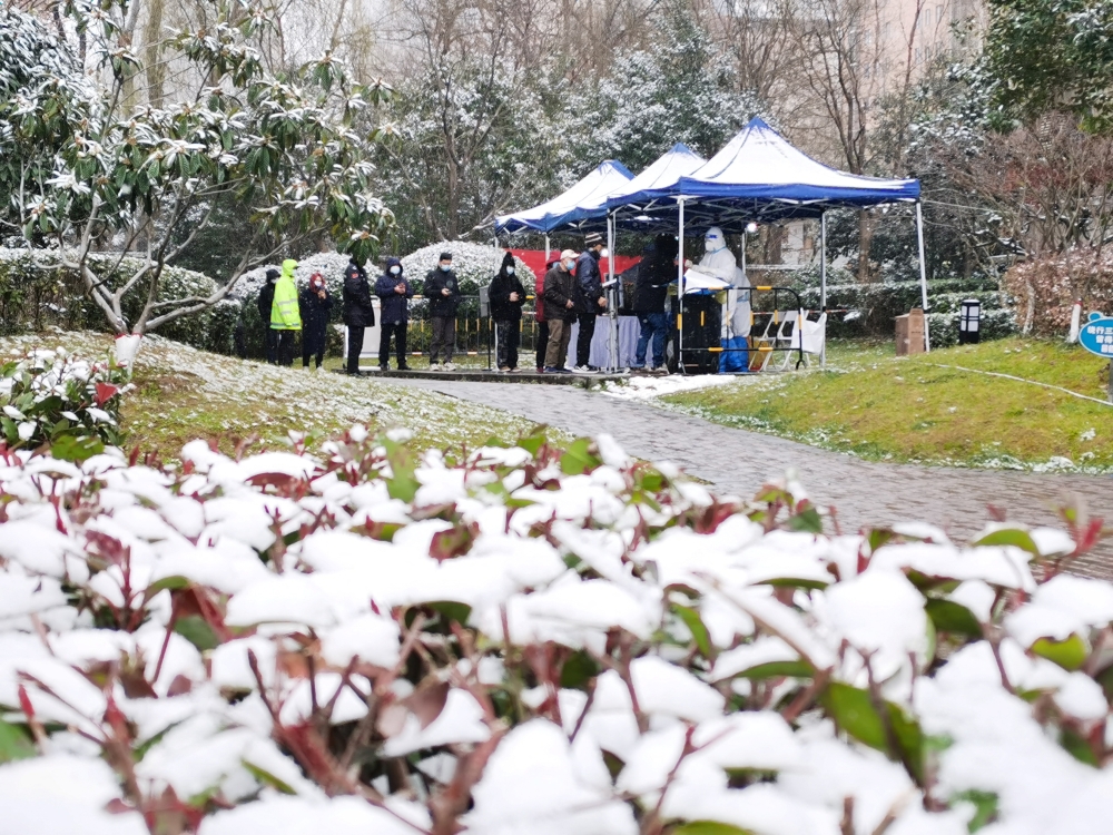 People line up in the snow for nucleic acid testing at a residential compound under lockdown following the coronavirus disease (COVID-19) outbreak in Yanta district of Xian, Shaanxi province, China December 25, 2021. Picture taken December 25, 2021. cnsphoto via REUTERS