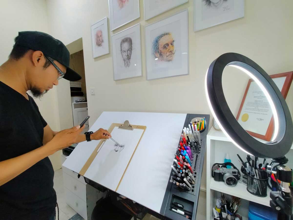 Arsenio Jr Nidoy scribbling a portrait in his studio