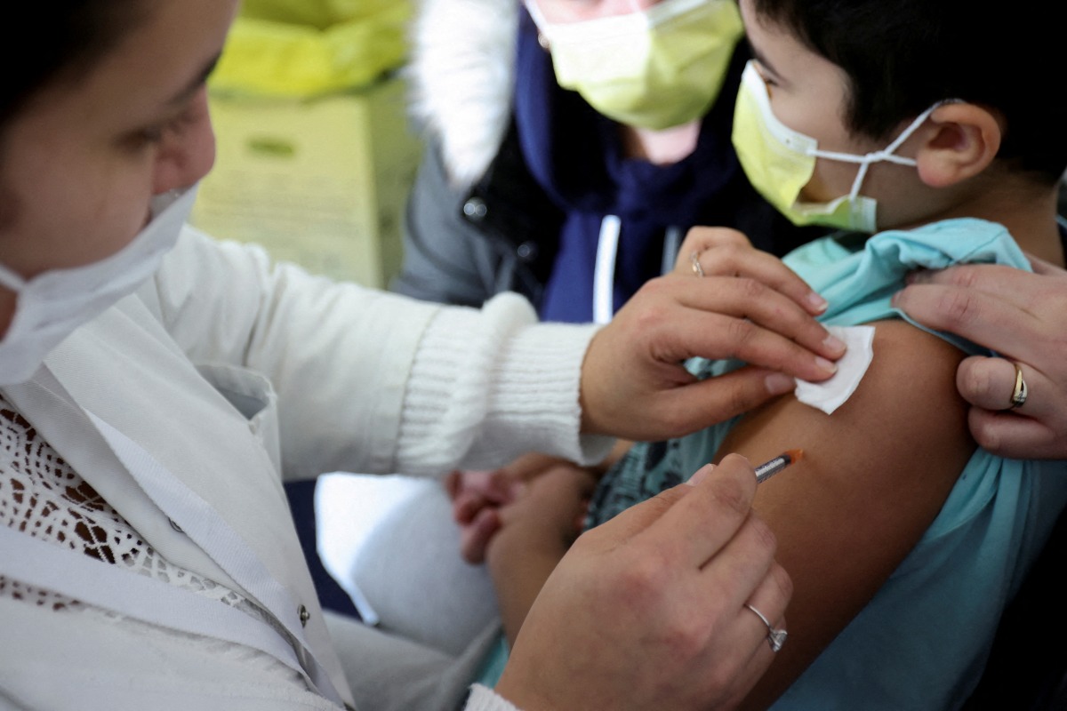 FILE PHOTO: A medical worker administers a dose of a coronavirus disease (COVID-19) vaccine to a child at a vaccination centre in Les Pavillons-sous-Bois, near Paris, France, December 18, 2021. REUTERS/Sarah Meyssonnier/File Photo
