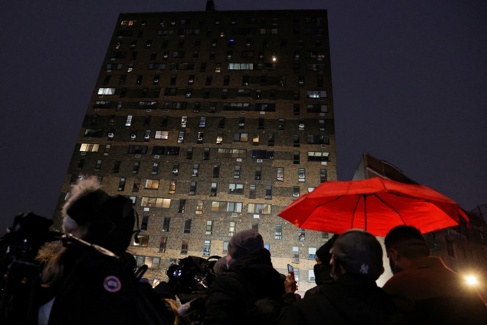 People stand outside an apartment building where a fire occurred in the Bronx borough of New York City, U.S., January 9, 2022. REUTERS/Andrew Kelly