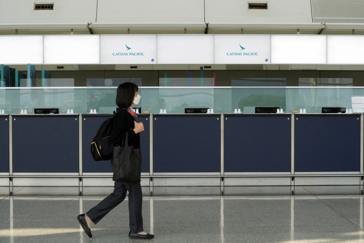 FILE PHOTO: A woman walks past empty counters of Cathay Pacific at Hong Kong International Airport following fresh measures to control coronavirus (COVID-19) infections in Hong Kong, China January 11, 2022. REUTERS/Lam Yik/File Photo
