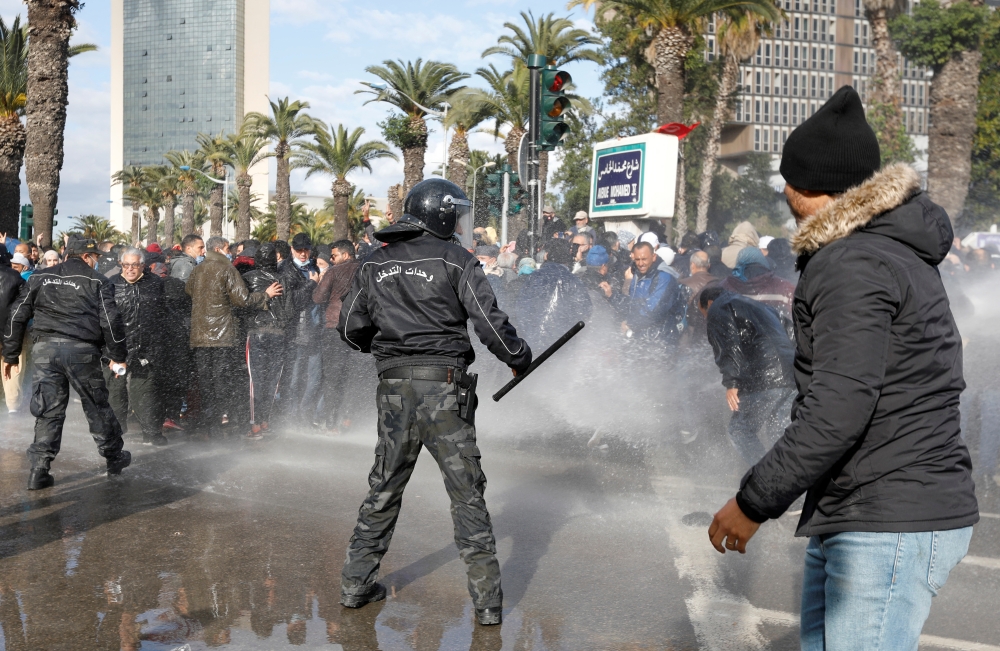 Demonstrators are hit by a water cannon during a protest against Tunisian President Kais Saied's seizure of governing powers, in Tunis, Tunisia, January 14, 2022. REUTERS/