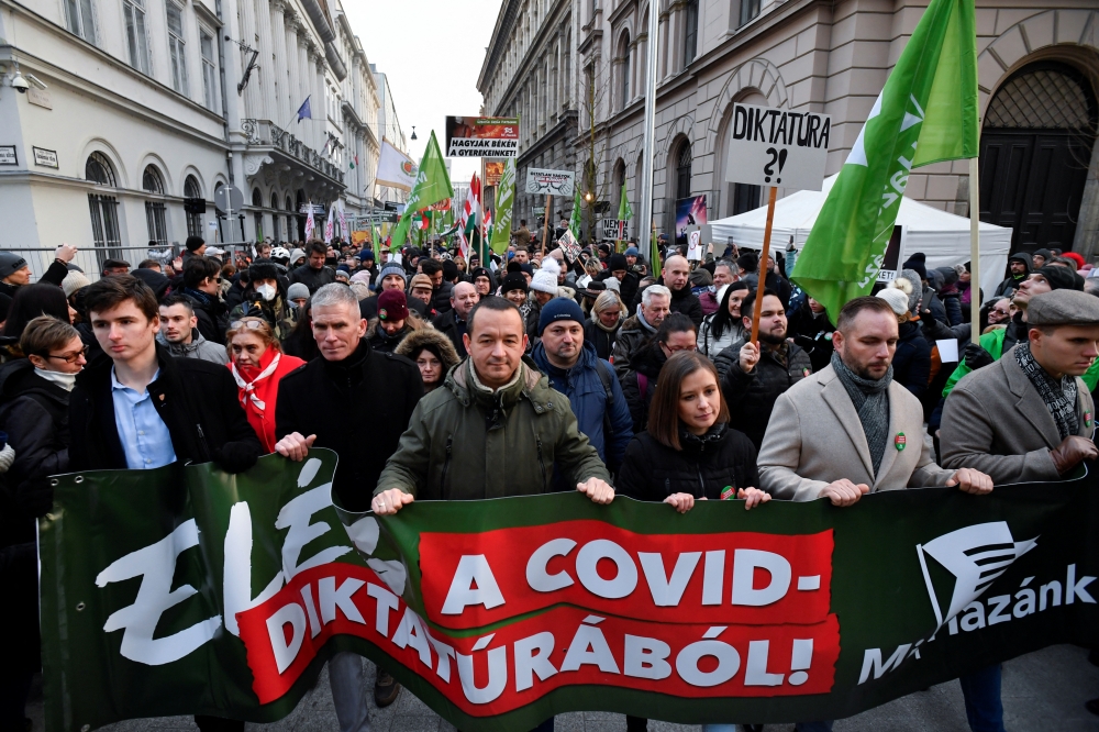 People hold signs during a protest against coronavirus disease (COVID-19) measures and vaccinations in front of the Ministry of Human Capacities, in Budapest, Hungary, January 16, 2022. REUTERS/Marton Monus

