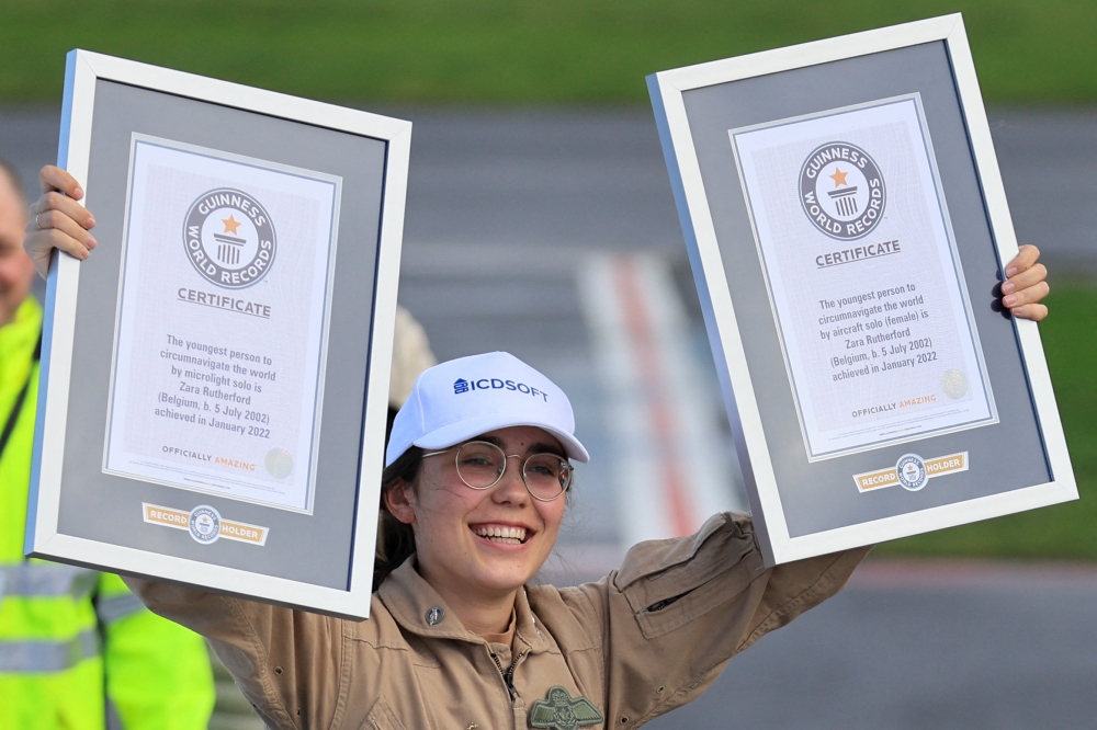 Belgian-British pilot Zara Rutherford, 19, holds her Guinness World Record certificates following her landing at Kortrijk-Wevelgem Airport, after a round-the-world trip in a light aircraft, becoming the youngest female pilot to circle the planet alone, in Wevelgem, Belgium, January 20, 2022. REUTERS/Pascal Rossignol