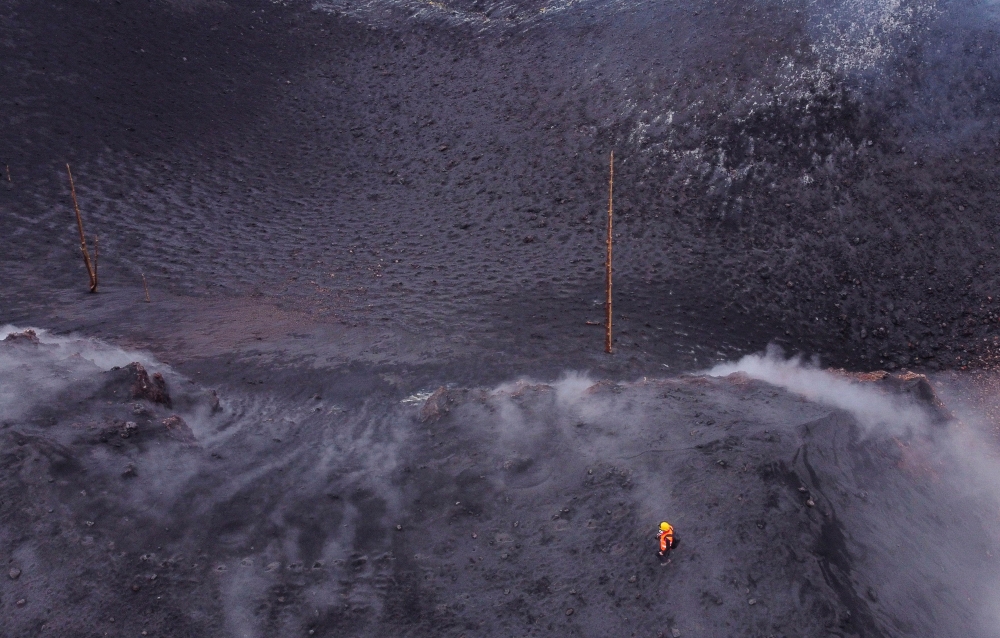 Members of the INVOLCAN technical team take measurements next to the crater of the Cumbre Vieja volcano, in Cabeza de Vaca, on the Canary Island of La Palma, Spain, January 21, 2022. Picture taken with a drone. REUTERS/Borja Suarez