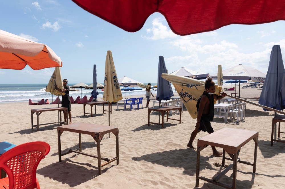 Workers pack up the parasols to close the beach as Indonesia imposes emergency measures, tightening restrictions in Java and Bali as coronavirus disease (COVID-19) cases surge, in Seminyak, Bali, Indonesia, July 3, 2021. REUTERS/Nyimas Laula/File Photo
