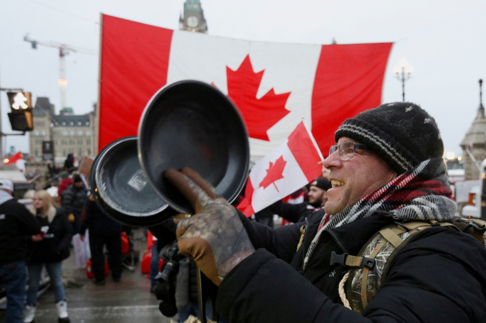 A person bangs pans as trucks honk their horns again, as truckers and supporters continue to protest coronavirus disease (COVID-19) vaccine mandates, in Ottawa, Ontario, Canada, February 11, 2022. Reuters/Lars Hagberg