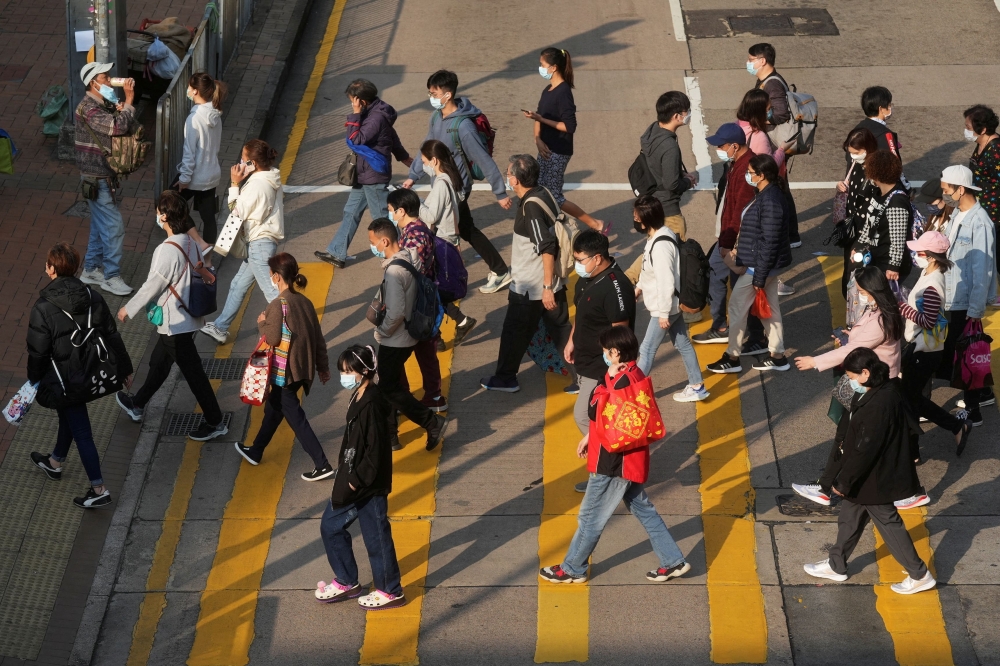 People wearing face masks cross a street following the coronavirus disease (COVID-19) outbreak, in Hong Kong, China February 15, 2022. REUTERS/Lam Yik/File Photo