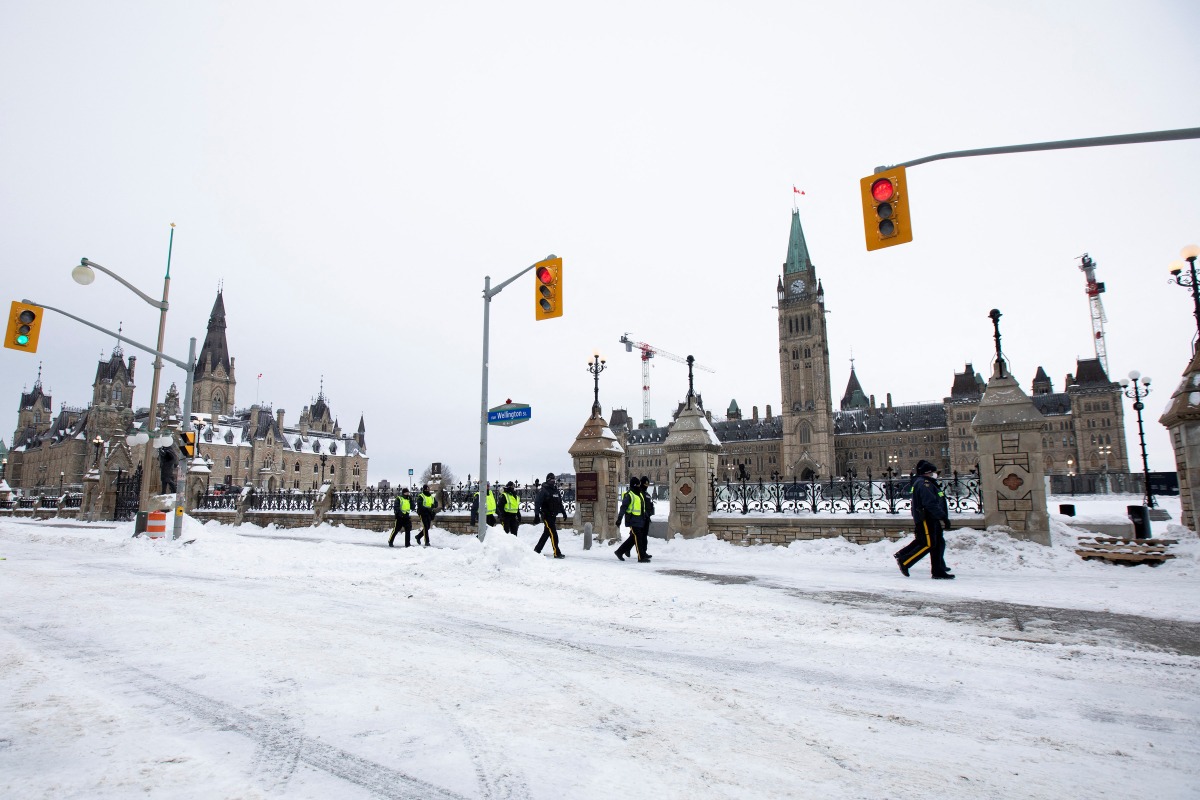 Police officers walk along Wellington Street as Canadian police worked to evict the last of the trucks and supporters occupying the downtown core, three weeks after a protest against coronavirus disease (COVID-19) vaccine mandates began in Ottawa, Ontario, Canada, February 20, 2022. REUTERS/Carlos Osorio
