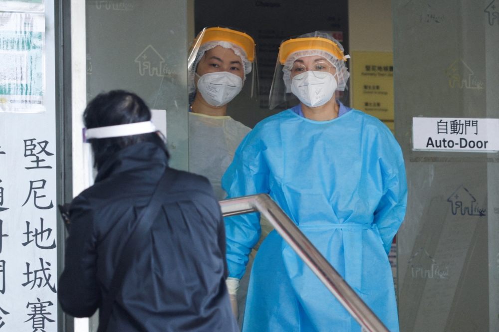 Healthcare workers wearing personal protective equipment (PPE) stand at a clinic designated to treat patients for the coronavirus disease (COVID-19), in Hong Kong, China March 7, 2022. REUTERS/Tyrone Siu