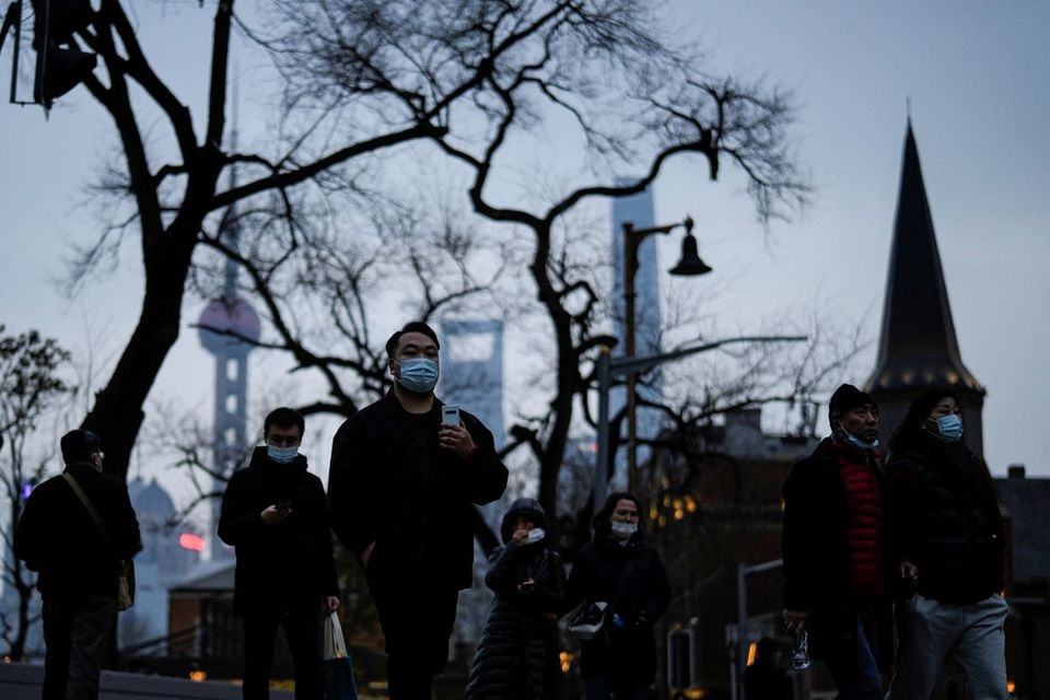 People wearing protective masks walk on street, following new coronavirus disease (COVID-19) cases in Shanghai, China February 14, 2022. REUTERS/Aly Song


