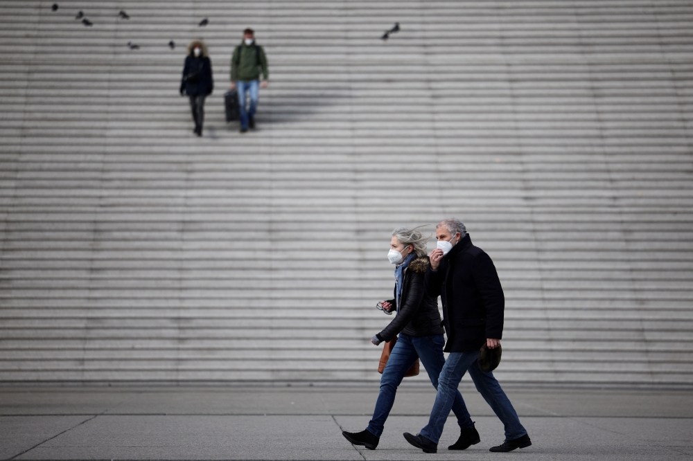 People, wearing protective face masks, walk past the steps near the Grande Arche at the financial and business district of La Defense in Puteaux near Paris, France, January 31, 2022. Reuters/Sarah Meyssonnier/File Photo