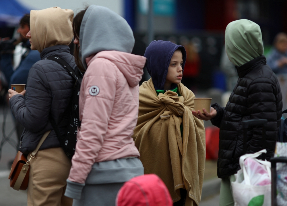 Ukrainian refugees wait outside a temporary shelter, after fleeing the Russian invasion of Ukraine, in Przemysl, Poland, March 29, 2022. REUTERS.