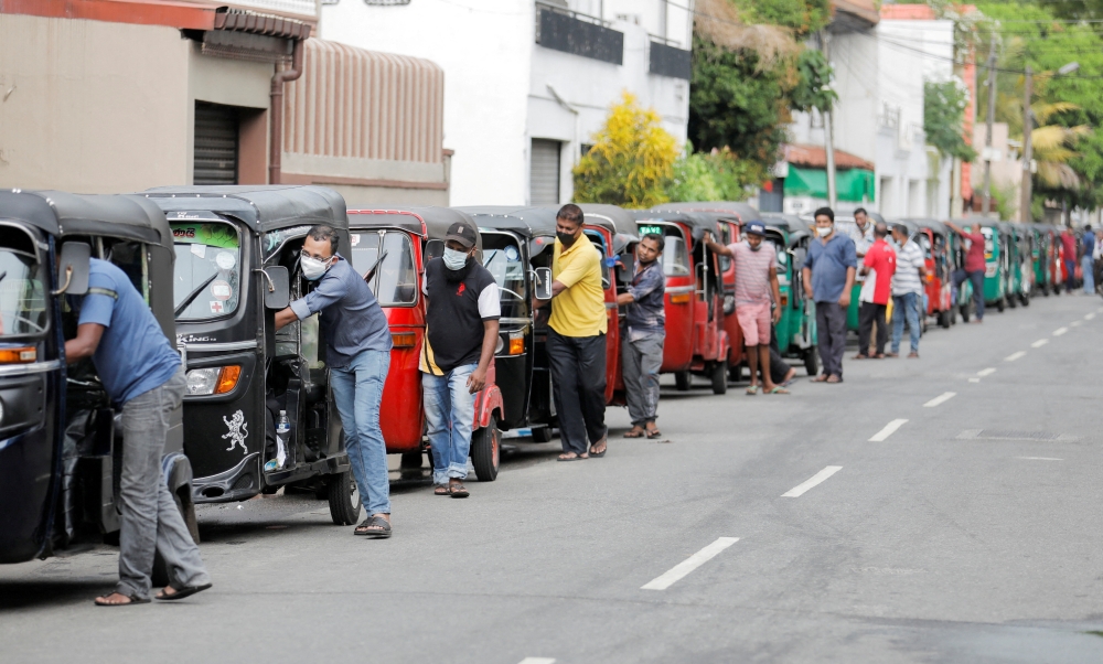 Drivers push their three-wheelers while waiting in a line to buy petrol at a Ceylon Ceypetco fuel station on a main road, amid the country's economic crisis in Colombo, Sri Lanka, April 12, 2022. REUTERS/Dinuka Liyanawatte/File Photo