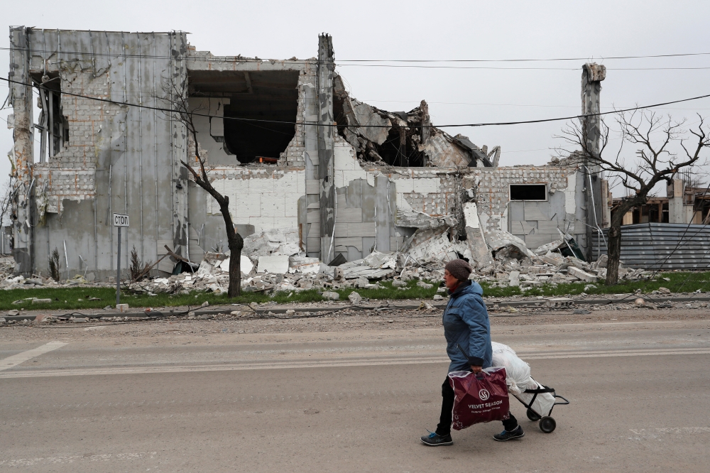 A local resident walks past a building destroyed during Ukraine-Russia conflict in the southern port city of Mariupol, Ukraine April 19, 2022. REUTERS/Alexander Ermochenko