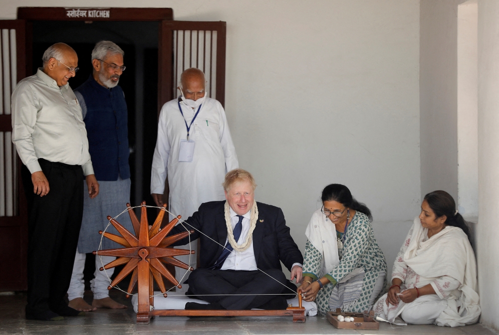 Britain's Prime Minister Boris Johnson spins cotton on a wheel during his visit to Gandhi Ashram in Ahmedabad, India, April 21, 2022. Reuters/Amit Dave 