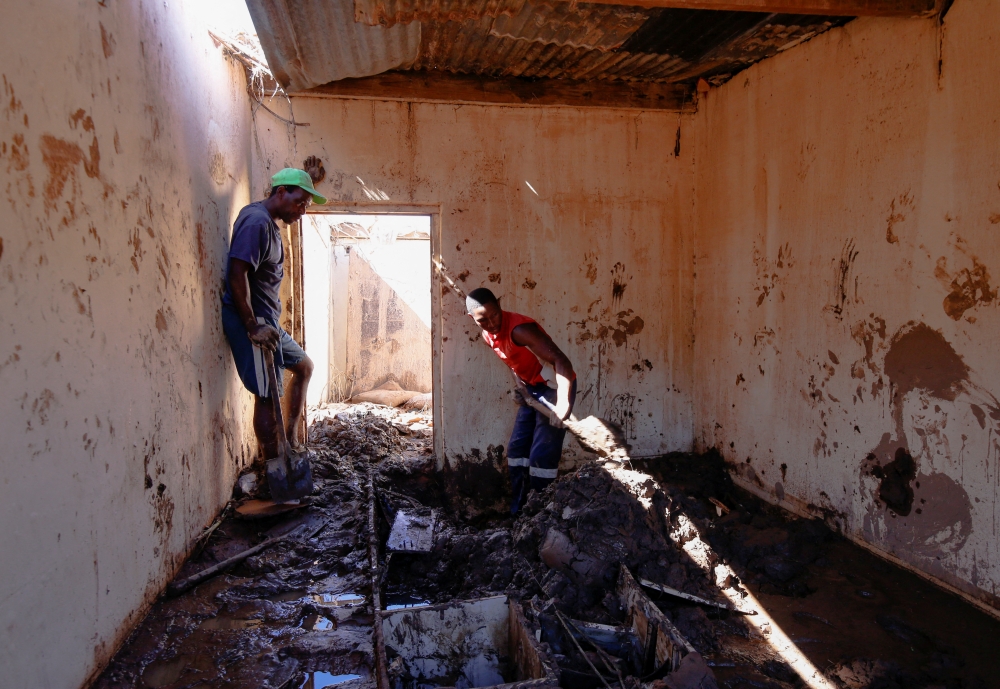 Men dig mud out of a house after heavy rains caused flooding in Ntuzuma near Durban, South Africa, April 20, 2022. REUTERS/Rogan Ward