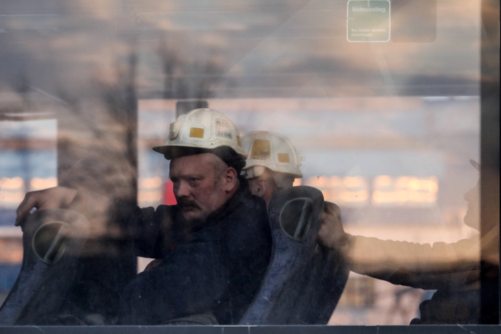 Miners looks from a window as search and rescue operation continues after a tremor at the Borynia-Zofiowka coal mine in Jastrzebie-Zdroj, Poland. April 23, 2022. Picture taken April 23, 2022. Dominik Gajda/Agencja Wyborcza.pl via REUTERS