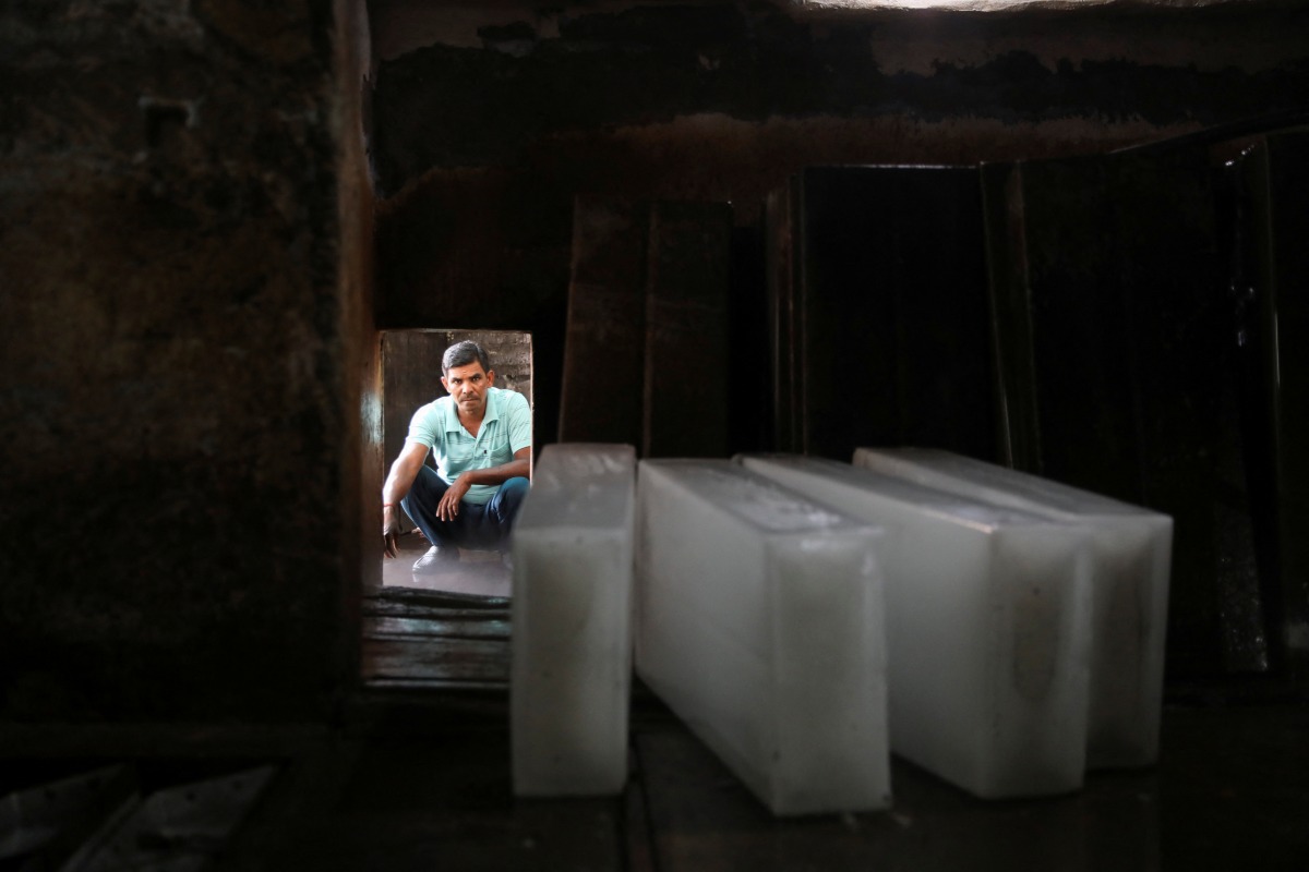 A worker waits to load ice blocks onto a truck, at an ice factory, on a hot summer day in New Delhi, India, May 1, 2022. REUTERS/Anushree Fadnavis
