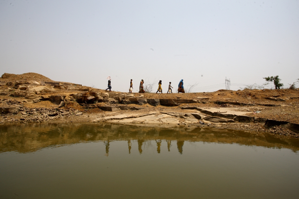 Women and children carry containers after filling them with water at an abandoned stone quarry on a hot day in Chipiya Abhaypur village in the northern state of Uttar Pradesh, India, May 4, 2022. Reuters/Ritesh Shukla