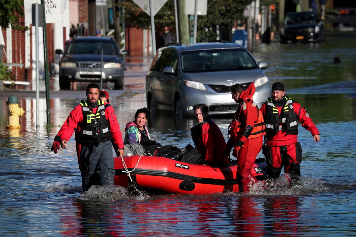 FILE PHOTO: First responders pull local residents in a boat as they perform rescues of people trapped by floodwaters after the remnants of Tropical Storm Ida brought drenching rain, flash floods and tornadoes to parts of the northeast in Mamaroneck, New York, U.S., September 2, 2021. REUTERS/Mike Segar/File Photo
