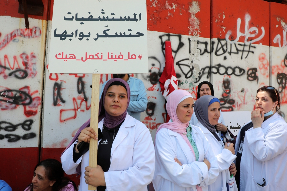 A healthcare worker holds a placard reading 