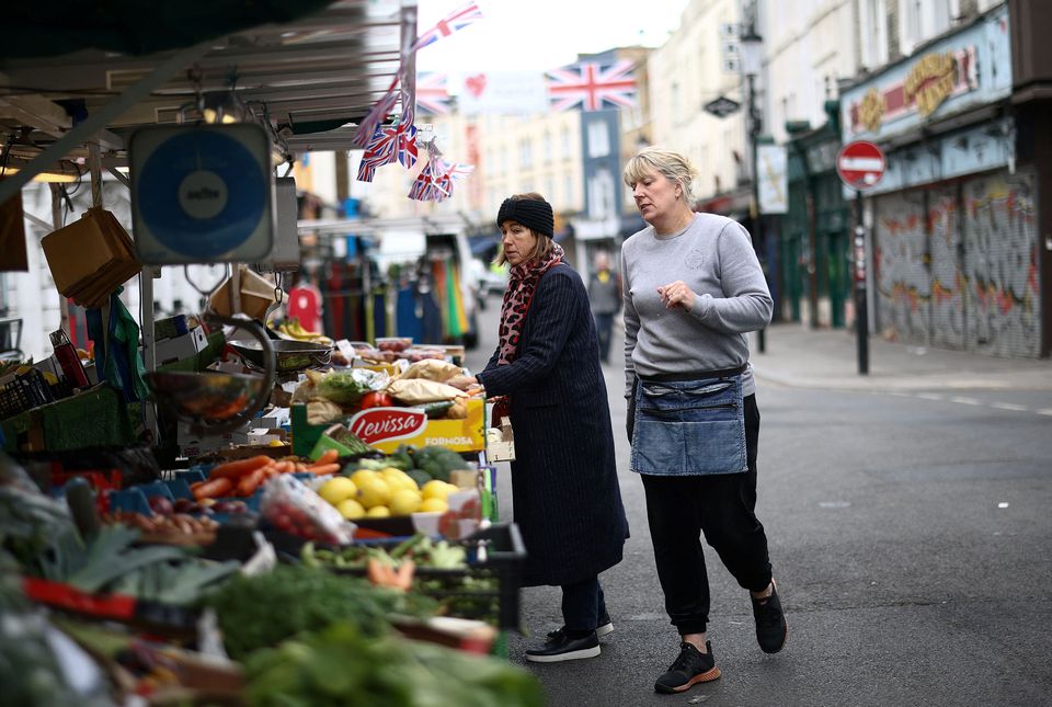 Kelly Wakeling assists a customer at her market stall ALK Fruit and Veg on Portobello Road, in London, Britain, May 30, 2022. REUTERS/Henry Nicholls


