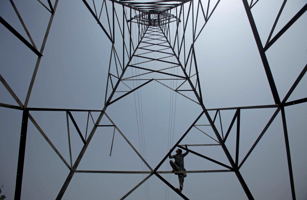 A worker of Peshawar Electric Supply Company (PESCO) climbs up a high-voltage pylon in Peshawar, Pakistan August 7, 2017. Reuters/Fayaz Aziz/File Photo
 