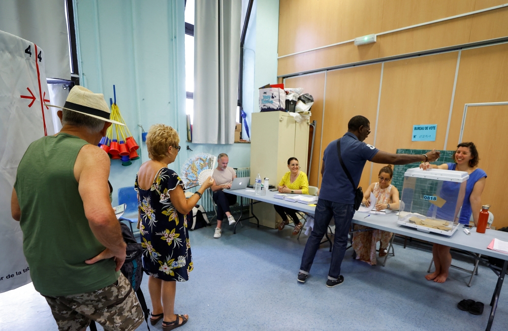 Voters stand in a voting booth to vote in the second round of the French parliamentary elections, at a polling station in Marseille, France, June 19 2022. Reuters/Eric Gaillard