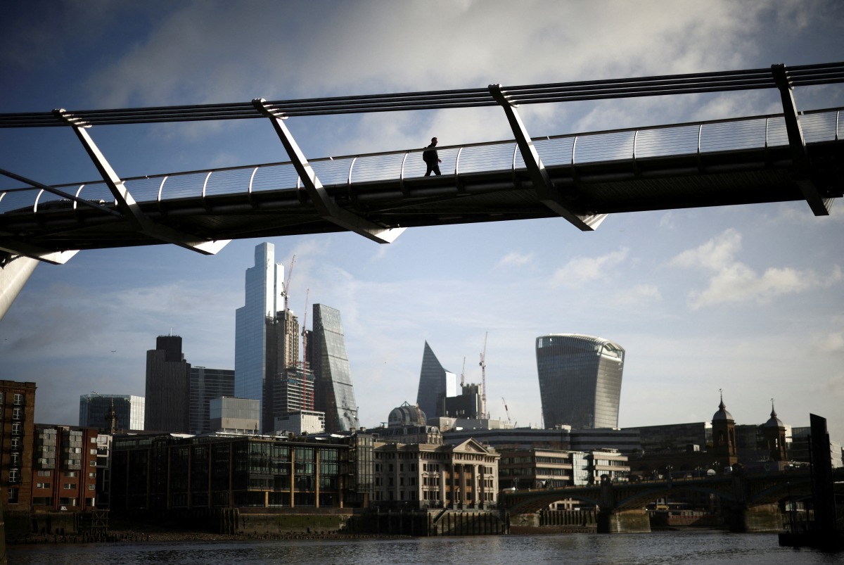 The City of London financial district is seen as people walk over Millennium Bridge in London, Britain, February 16, 2022. REUTERS/Henry Nicholls/File Photo

