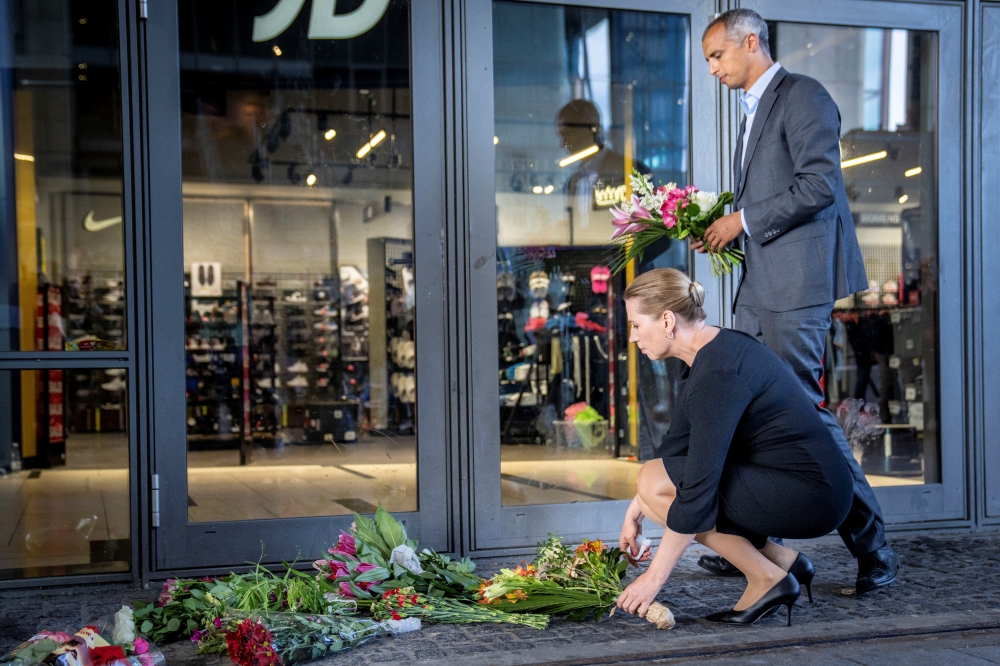 Danish Prime Minister Mette Frederiksen and Justice Minister Mattias Tesfaye lay flowers outside Field's shopping centre before their news conference, a day after a shooting occurred at the mall, in Copenhagen, Denmark, July 4, 2022. (Reuters)