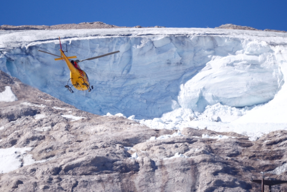 A helicopter participates in a search and rescue operation over the site of a deadly collapse of parts of a mountain glacier in the Italian Alps amid record temperatures, at Marmolada ridge, Italy July 6, 2022. REUTERS/Guglielmo Mangiapane