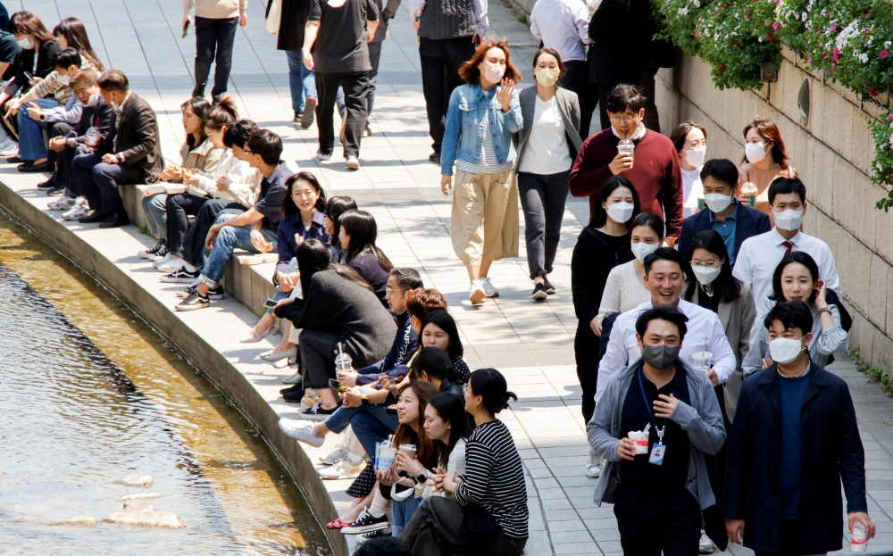 People wear masks to prevent the spread of the coronavirus disease (COVID-19) as they take a walk on a sunny spring day in Seoul, South Korea, May 3, 2022. REUTERS/ Heo Ran/File Photo