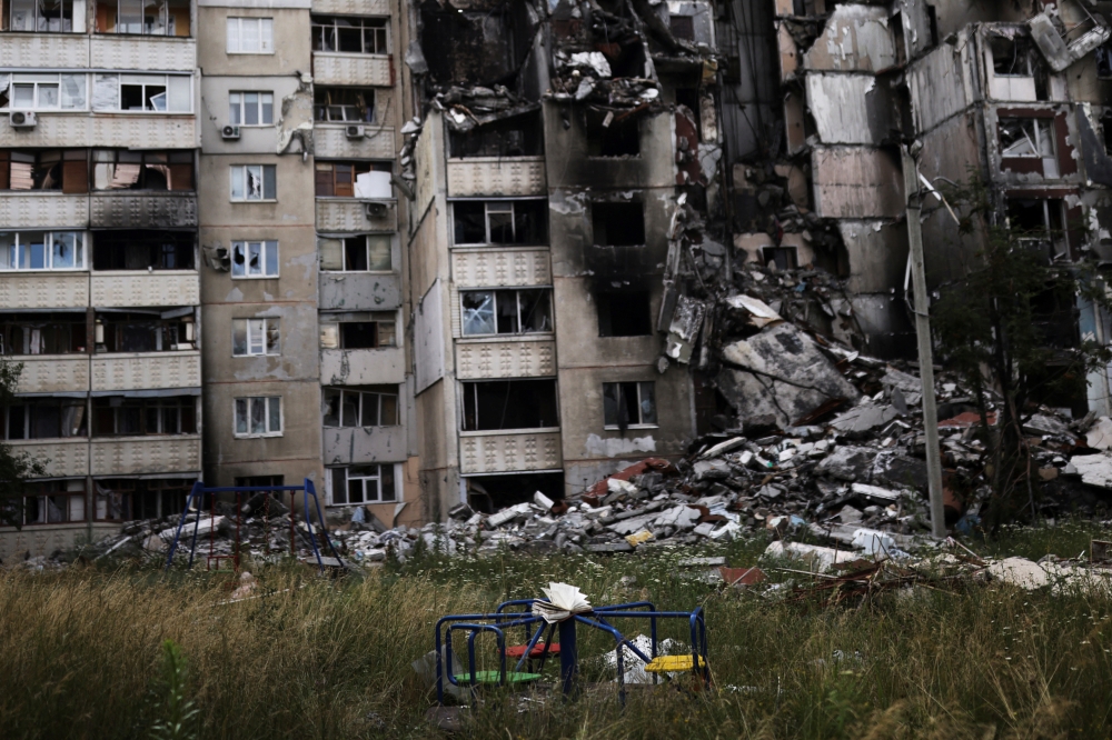 A book is seen on a playground in front of a building destroyed by a military strike, as Russia's invasion of Ukraine continues, in northern Saltivka, in Kharkiv, Ukraine, July 13, 2022. (REUTERS/Nacho Doce)