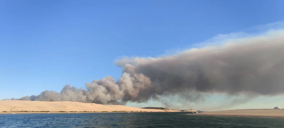 A general view shows smoke rising from the Gironde forest fires as seen from Dune de Pilat, Arcachon Bay, France July 12, 2022 in this picture obtained from social media. Quentin/via REUTERS


