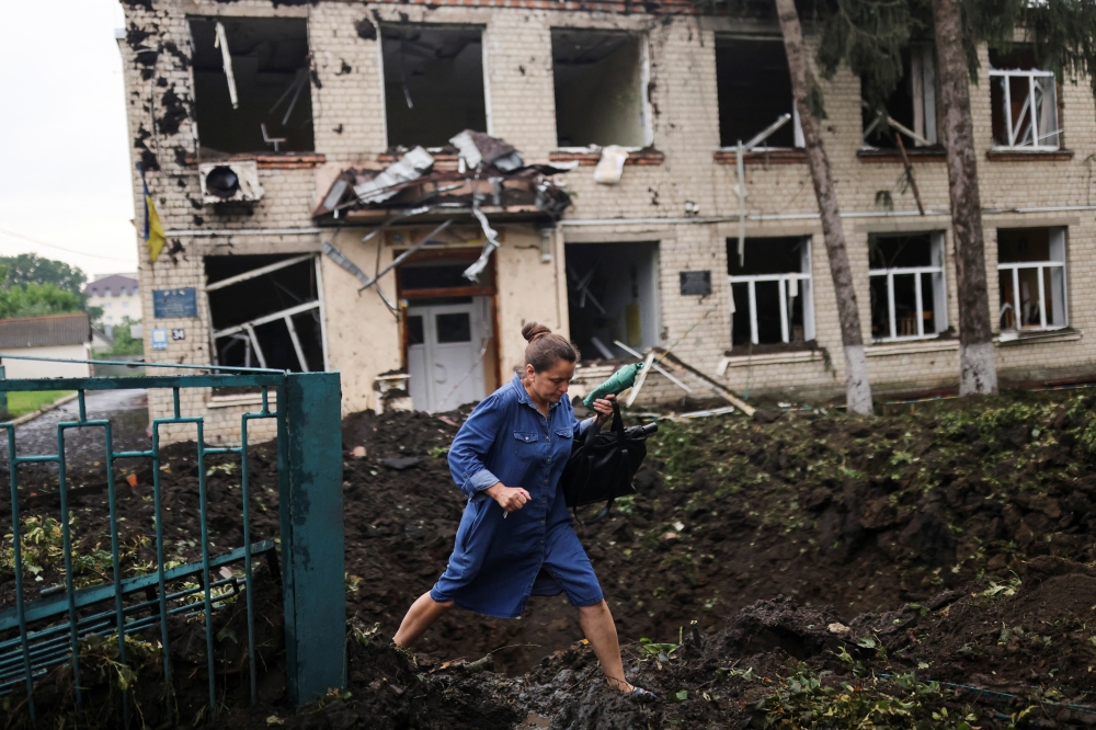 A teacher walks in front of a destroyed school following a military strike in Chuhuiv in Kharkiv region, Ukraine on July 16, 2022. (Reuters/Nacho Doce)