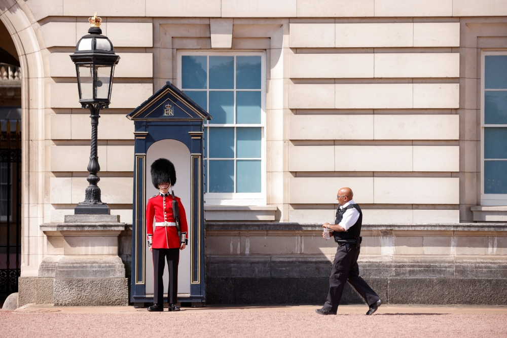 A police officer approaches with a bottle of water to give to a member of the Queen's Guard, during the hot weather, outside Buckingham Palace in London, Britain, July 18, 2022. (REUTERS/John Sibley)