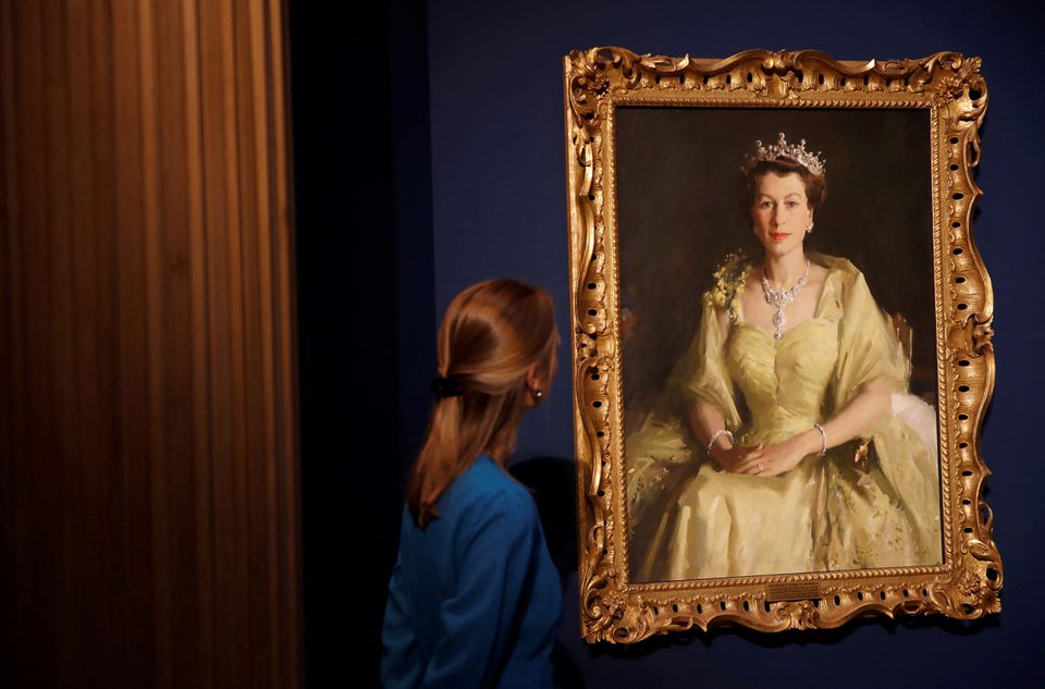 A staff member of the Royal Collection Trust poses for a photograph next to a painting known as the Wattle Portrait and is part of, Platinum Jubilee: The Queen’s Coronation exhibition at Windsor Castle, Windsor, Britain, July 6, 2022. REUTERS/Peter Nicholls
