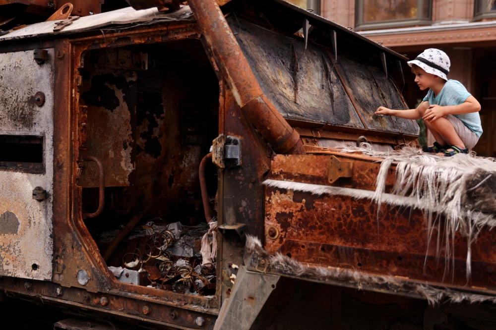 A boy looks at a destroyed tank during an exhibition displaying destroyed Russian military vehicles, as Russia's invasion of Ukraine continues, in Kiev, Ukraine, on August 20, 2022. 