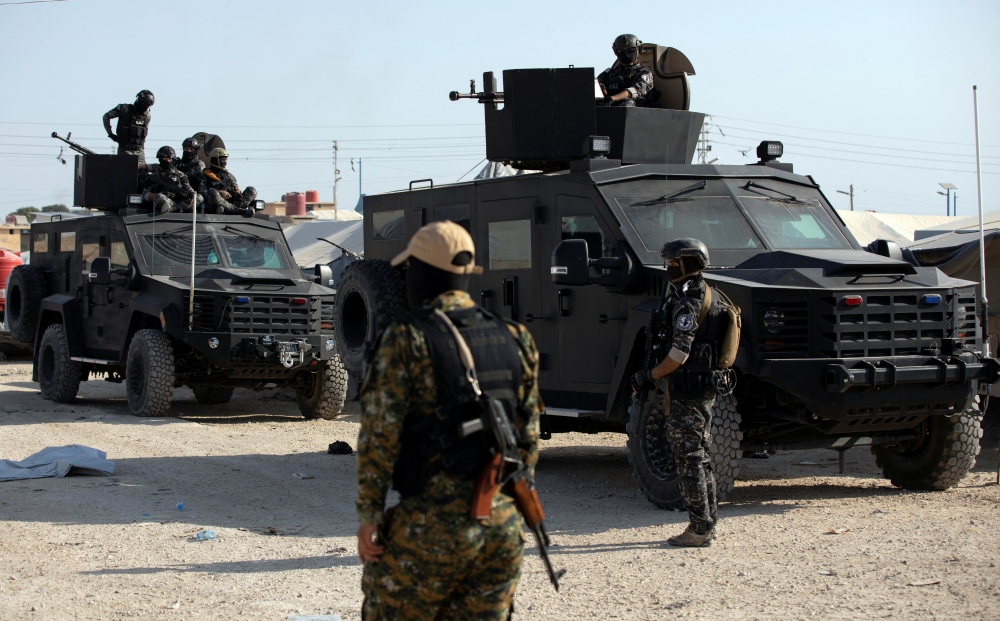 A Syrian Democratic Forces (SDF) fighter stands near Kurdish internal security special forces during a security operation in al-Hol camp which holds displaced people and families of Islamic State fighters, in Hasaka governorate, in northeast Syria August 26, 2022. REUTERS/Orhan Qereman