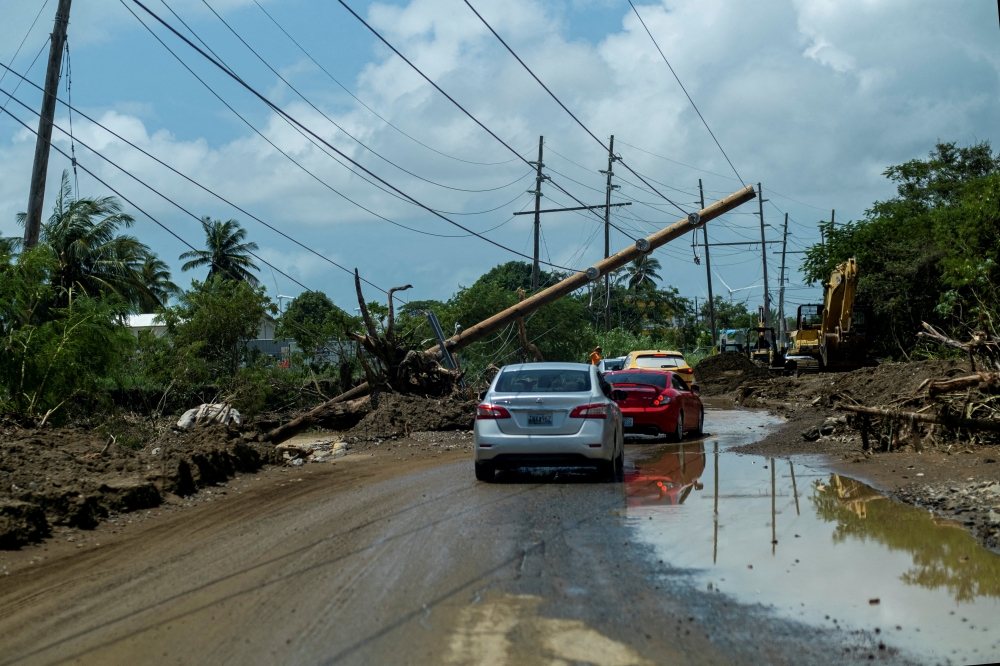 File photo: Cars drive under a downed power pole in the aftermath of Hurricane Fiona in Santa Isabel, Puerto Rico September 21, 2022. Reuters/Ricardo Arduengo/File Photo