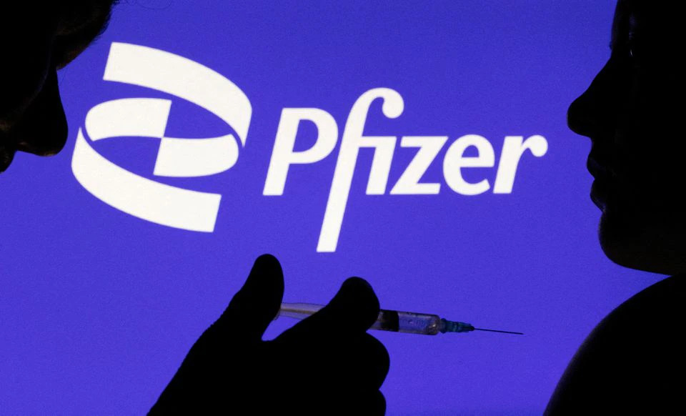 People pose with syringe with needle in front of displayed Pfizer logo in this illustration taken, on December 11, 2021. File Photo / Reuters
