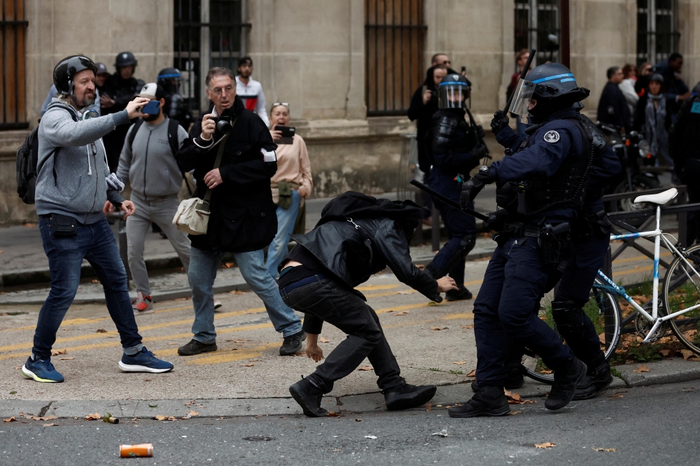 French riot police clash with a protestor at a demonstration in Paris as part of a nationwide day of strike and protests for higher wages and against requisitions at refineries in France, October 18, 2022. Reuters/Benoit Tessier