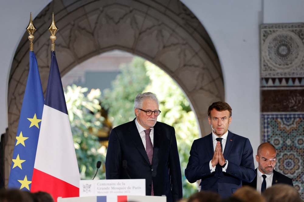 French President Emmanuel Macron joins hands before giving the highest French order of merit Legion of Honor (Legion d'Honneur) to Rector of Paris' Grand Mosque Chems-Eddine Hafiz, during a visit for the commemorative century exposition of the opening of the Grande Mosque of Paris, in Paris, France, on October 19, 2022.  Ludovic MARIN/Pool via REUTERS